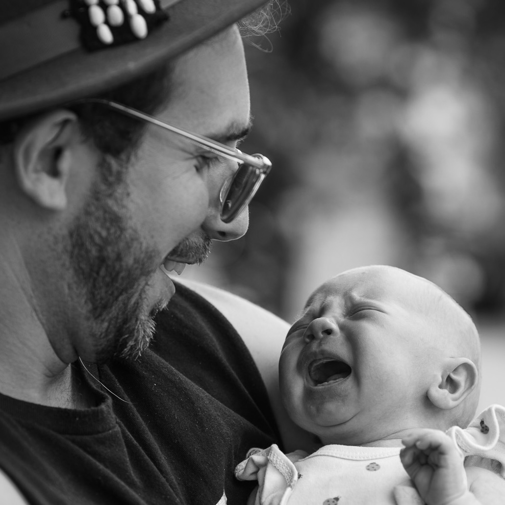 Blake, smiling as he holds his baby daughter