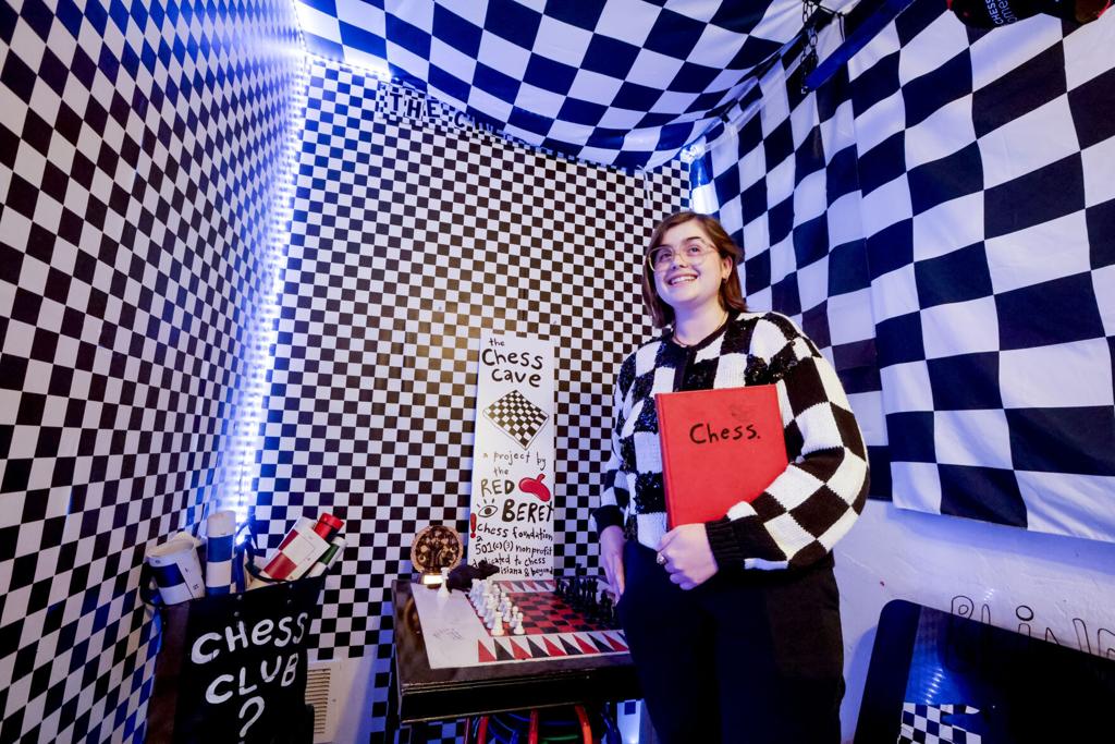 baylee badawy standing in the chess cave holding a red chess book